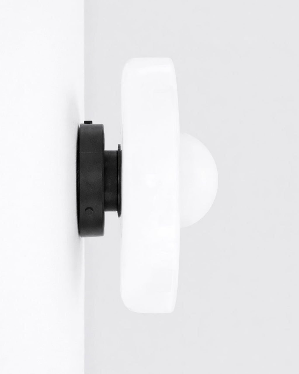 Round glass light fixture shown on wall