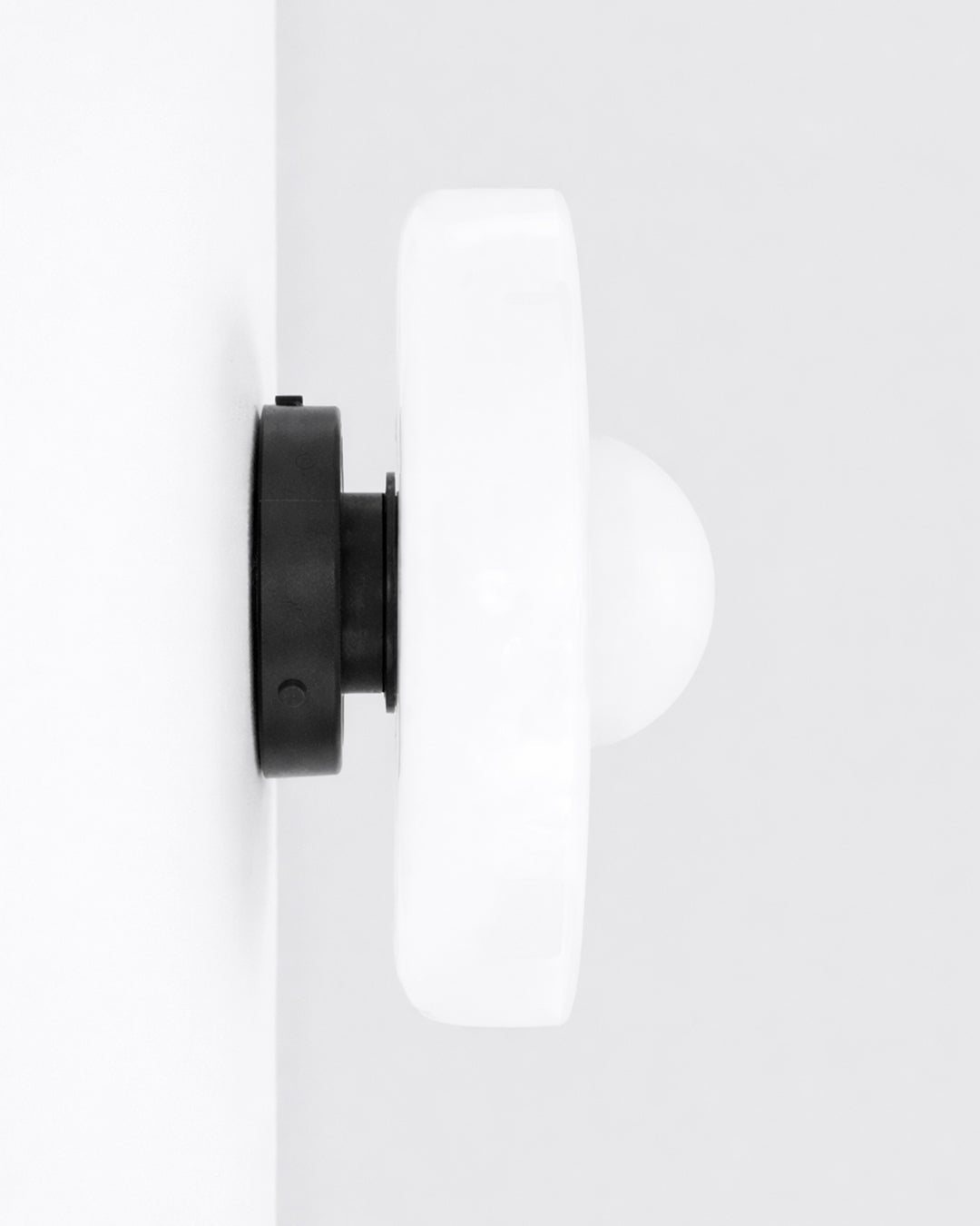 Round glass light fixture shown on wall