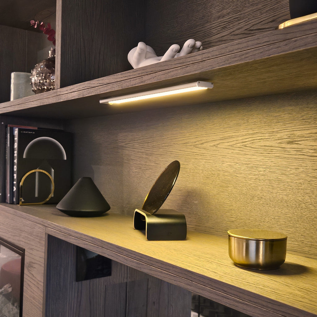 Motion sensor LED bar lighting a dark wood display shelf