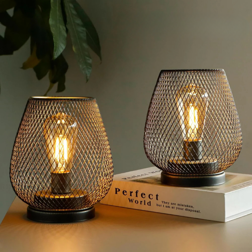 Two cordless table lamps glowing on a desk beside a book