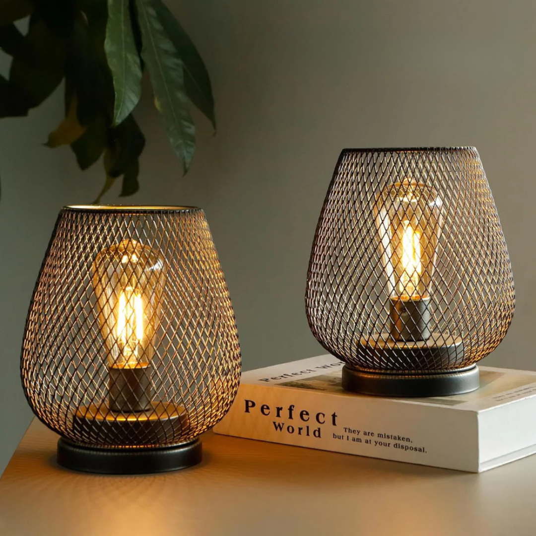 Two cordless table lamps glowing on a desk beside a book