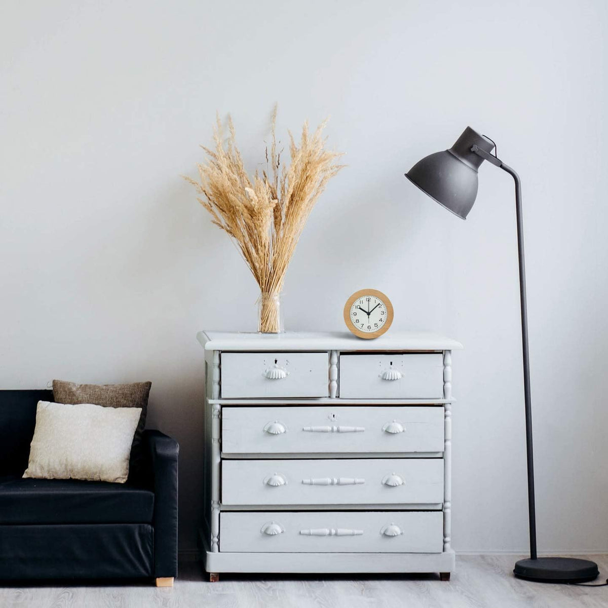 Beech wood alarm clock on a white dresser beside dried grass