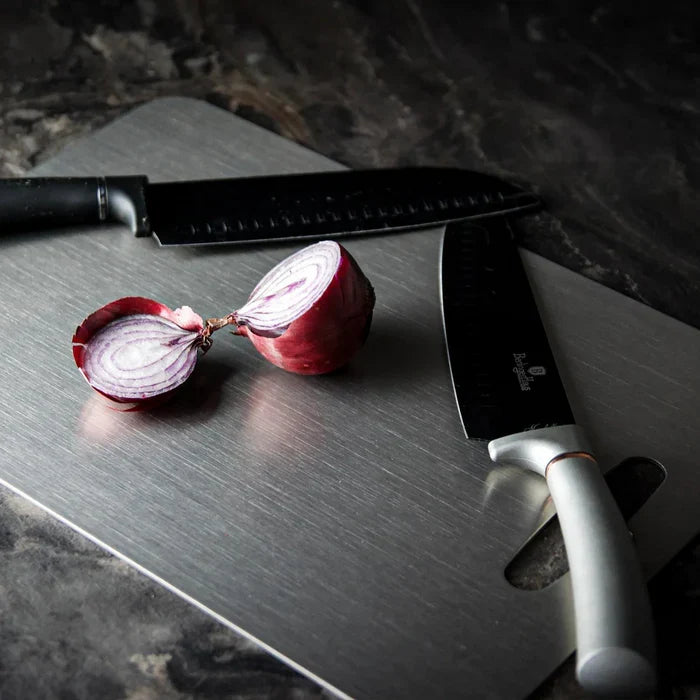 Red onion and knives on a stainless steel cutting board