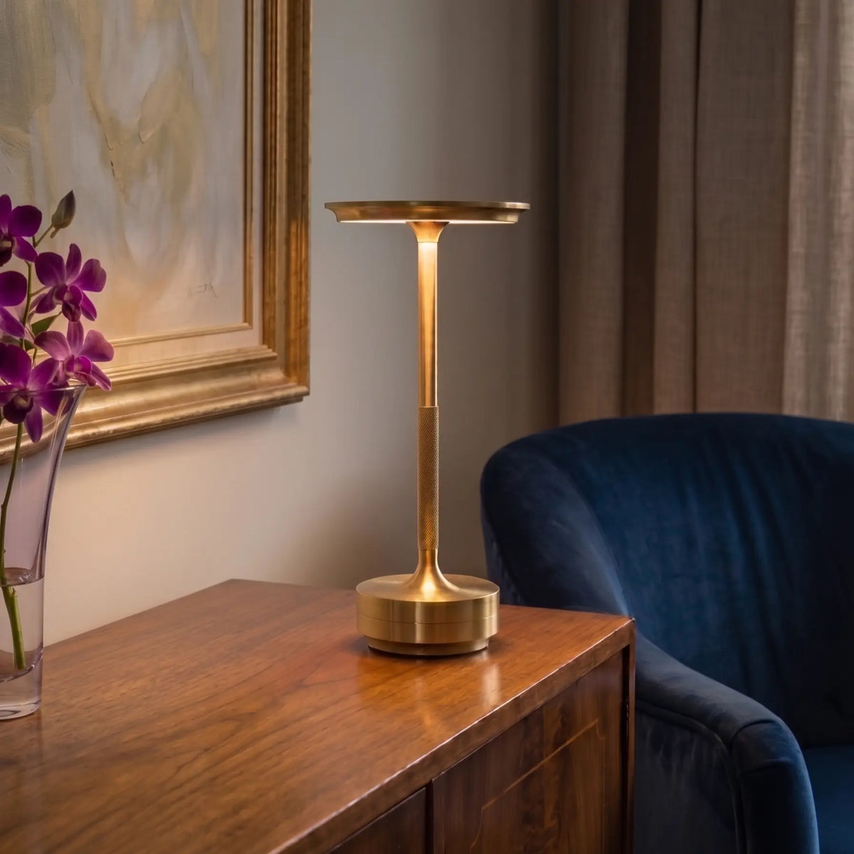 Gold table lamp standing next to a vase of flowers