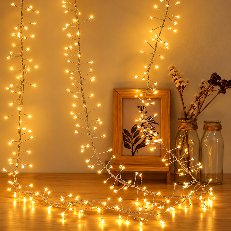 Warm white cluster string lights draped beside a wooden frame and vases