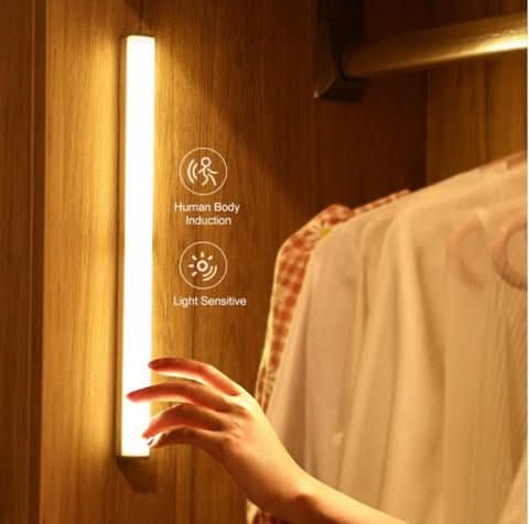 Vertical LED light bar mounted inside a closet beside hanging shirts