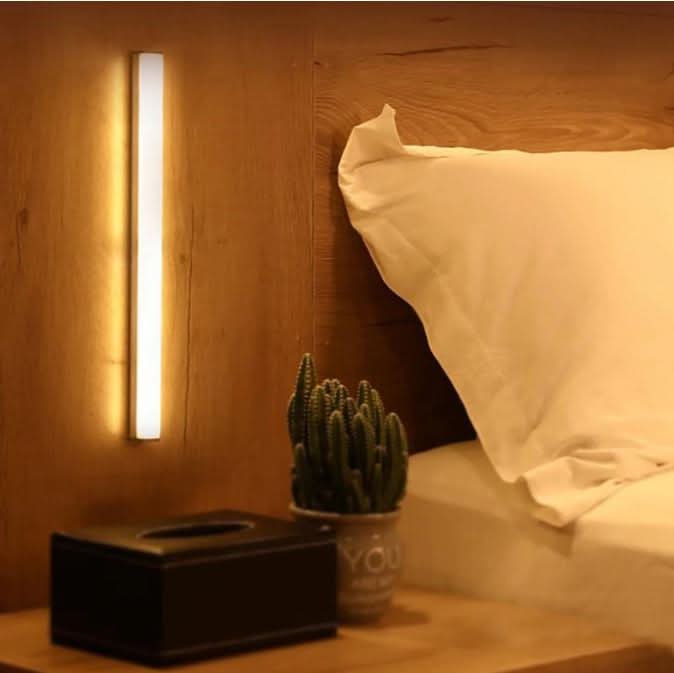 Wall-mounted LED light bar beside a bed and nightstand