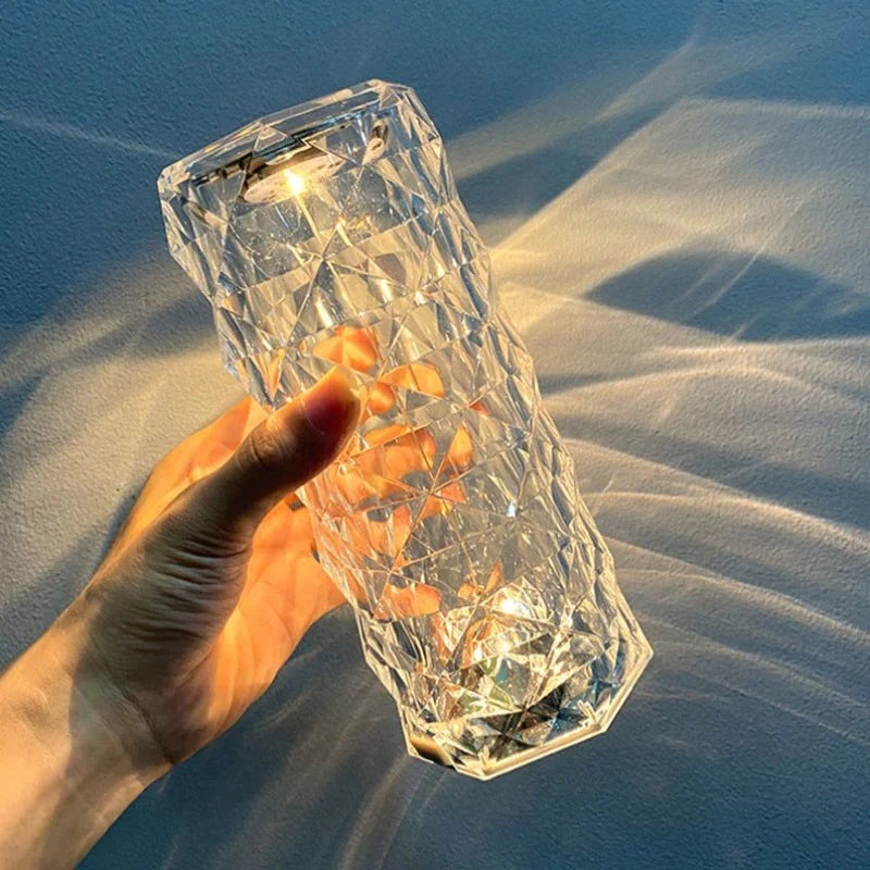 Hand holding a small table lamp with faceted acrylic body