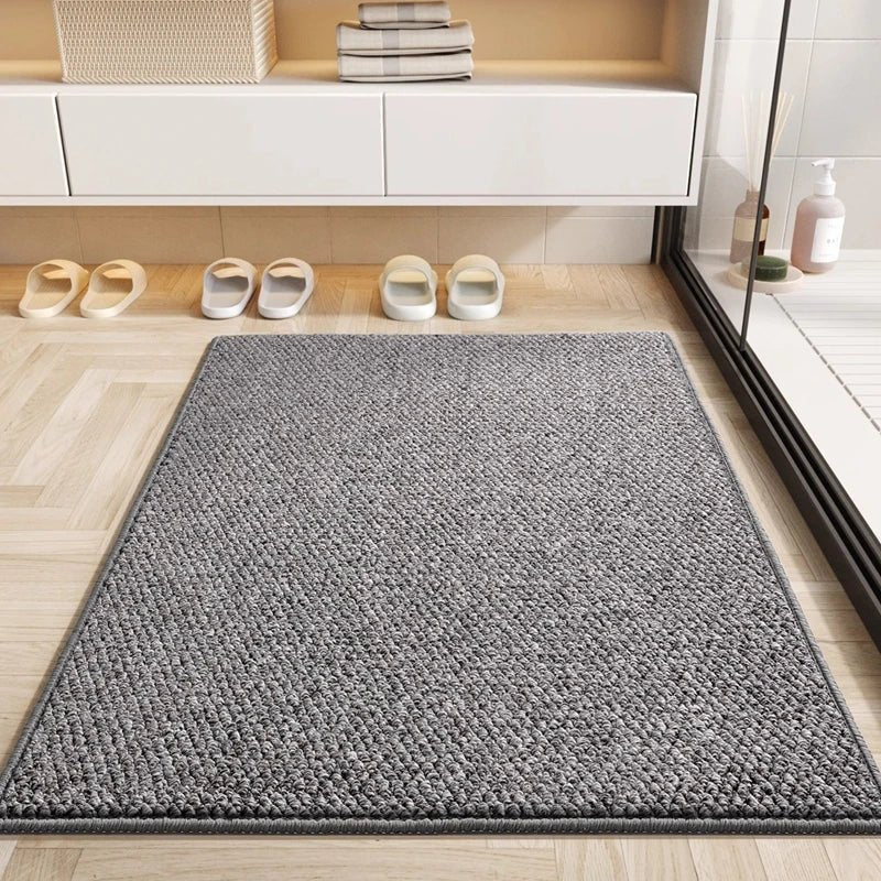 Gray absorbent doormat on herringbone floor by a shower