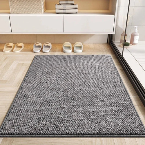 Gray absorbent doormat on herringbone floor by a shower
