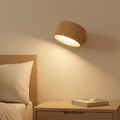 Natural Oak LED wall light glowing above a bedside table