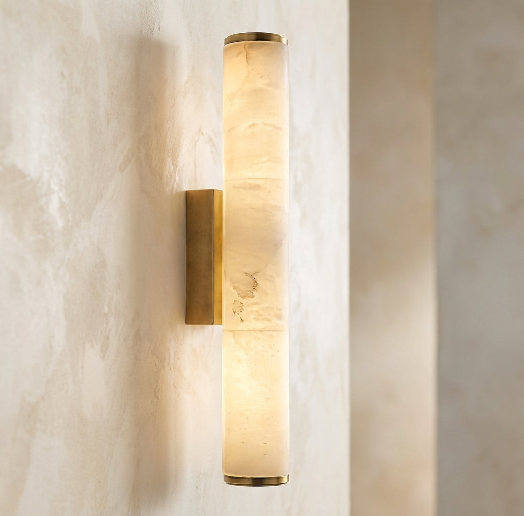 Slim marble-effect sconce glowing softly on a plaster wall