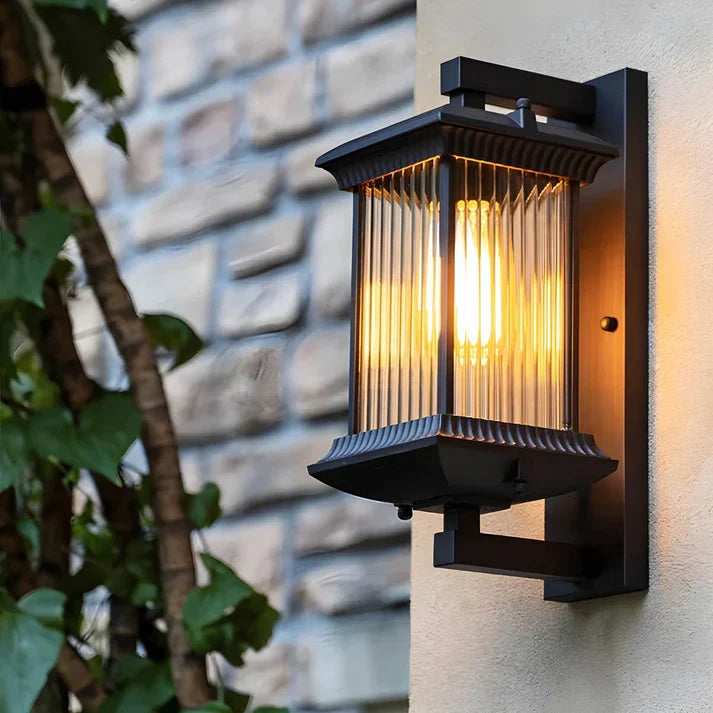 Outdoor wall lantern glowing on a stone and stucco wall