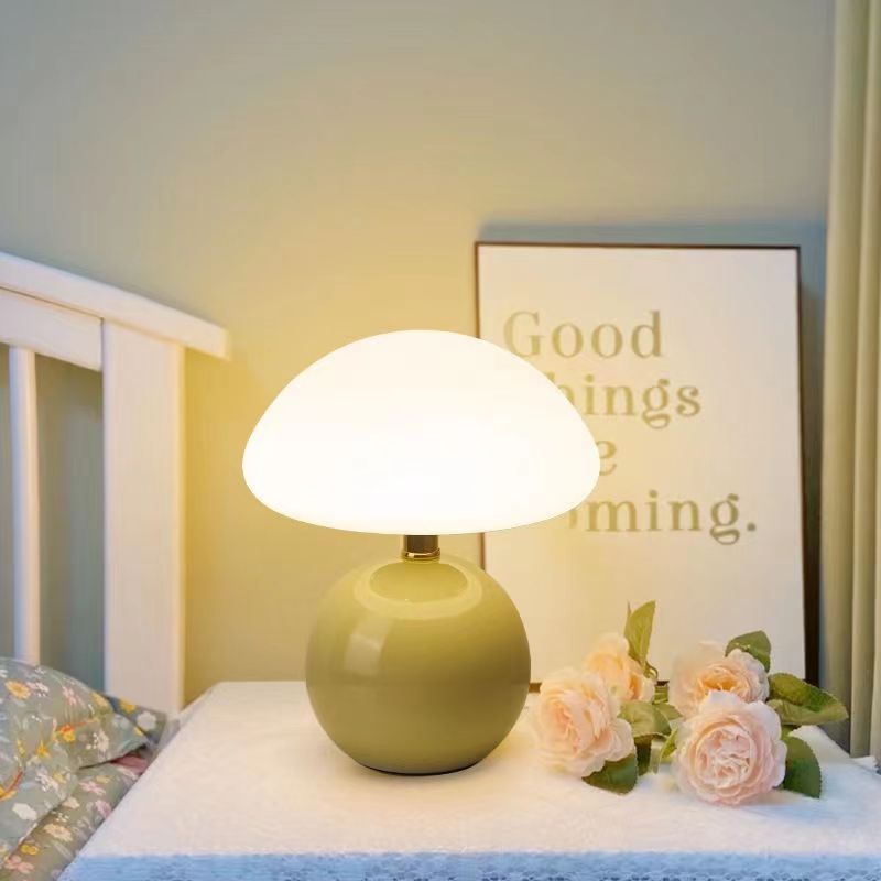 Soft green ceramic lamp with pink roses on a nightstand