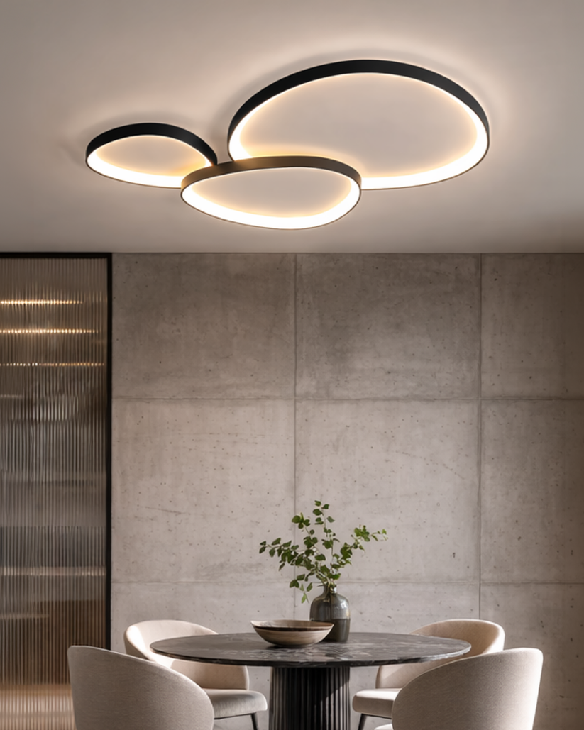 Black LED ceiling light with three pebble shapes above a dining table