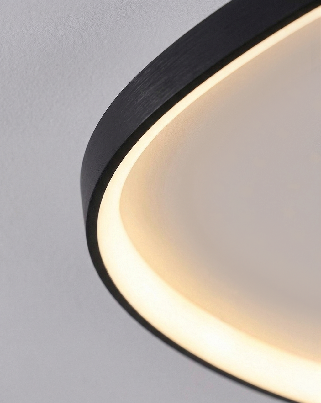 Black sculptural ceiling light glowing warm in an evening setting