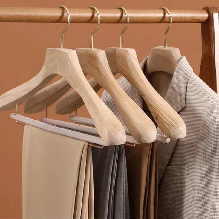 Wooden hangers holding a houndstooth blazer and folded trousers