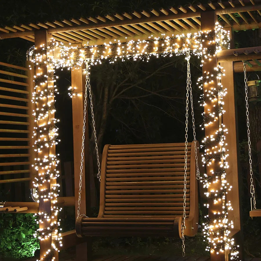 White string Christmas lights wrapped around a garden pergola swing