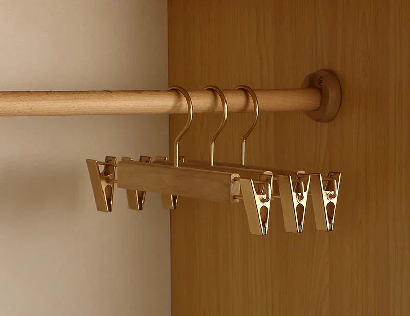 Wooden trouser hangers with champagne metal clips on a rail