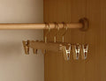 Wooden trouser hangers with champagne metal clips on a rail