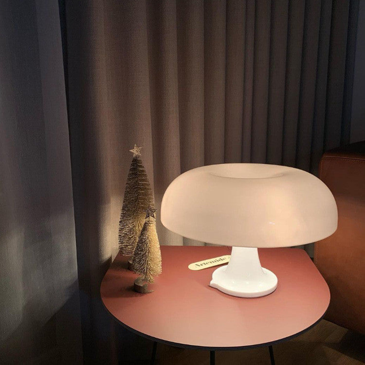 White mushroom table lamp glowing on a round side table