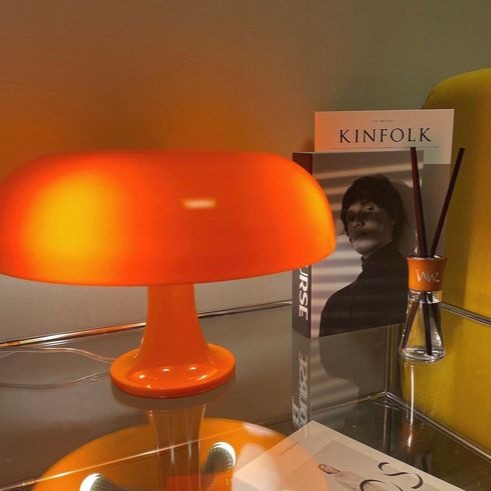 Orange mushroom light glowing beside books and a reed diffuser