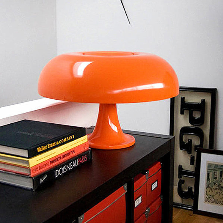 Orange modern table lamp on a black dresser with books