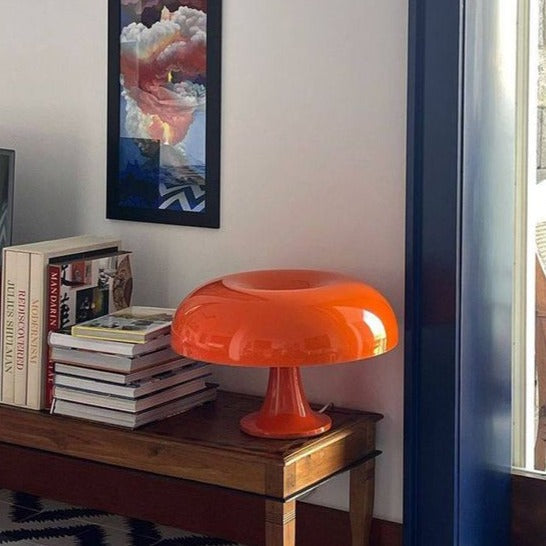 Orange small table lamp on a wooden bench by a window