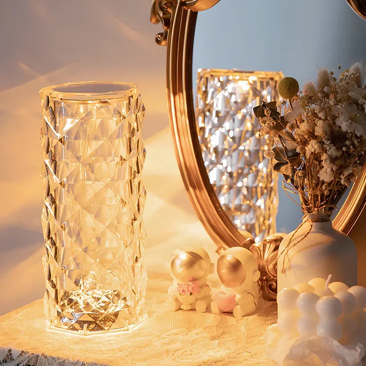 Touch table lamp glowing on a dresser beside a gold mirror