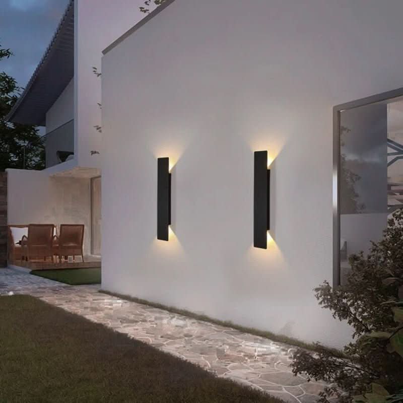 Pair of black modern wall lamps lighting a white wall