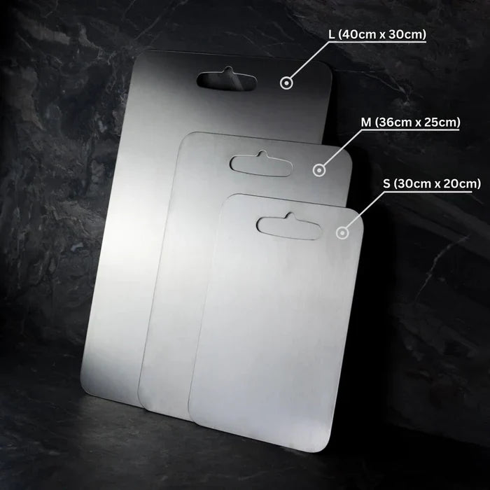 Three stainless steel cutting board sizes leaning against stone wall