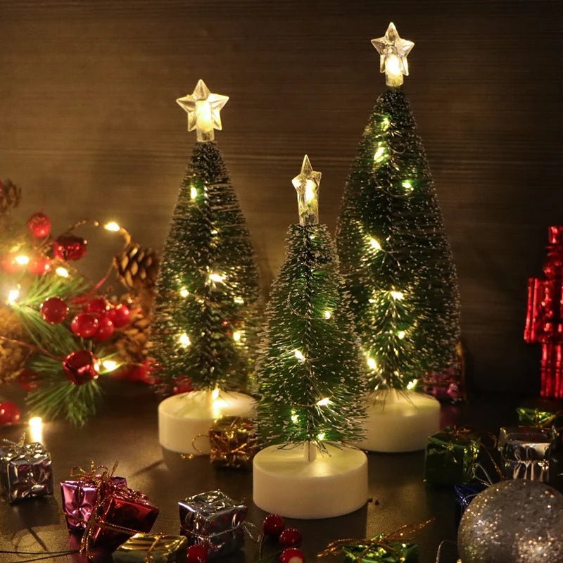 Three tabletop Christmas trees with lights among wrapped gifts
