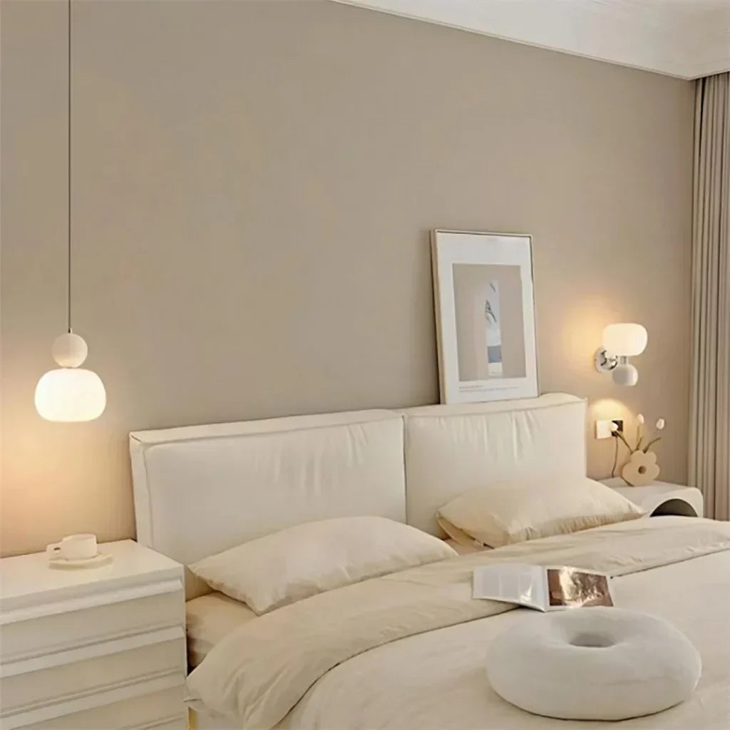 Cream pendant lamp hanging beside a white upholstered bed