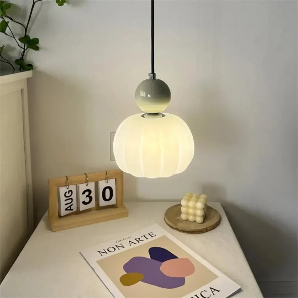 Ribbed frosted shade pendant glowing above a white nightstand