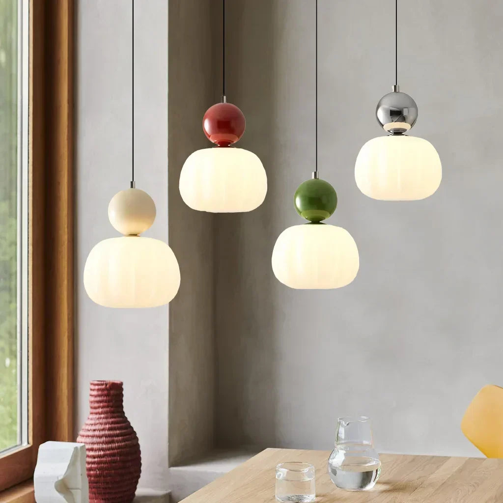 Hanging ceiling lamps in four colors above a wooden dining table