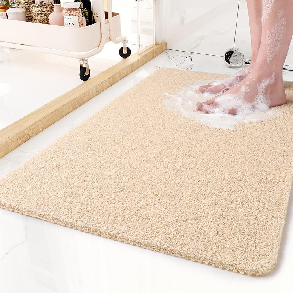 Beige non-slip shower mat beside a glass shower door