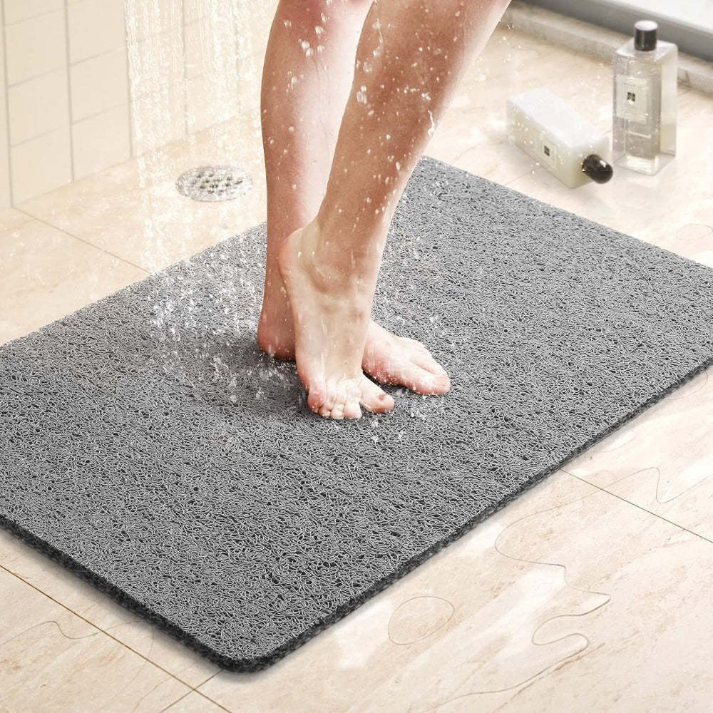 Gray non-slip shower mat under running shower water