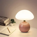 Pink modern lamp glowing on a desk beside open books