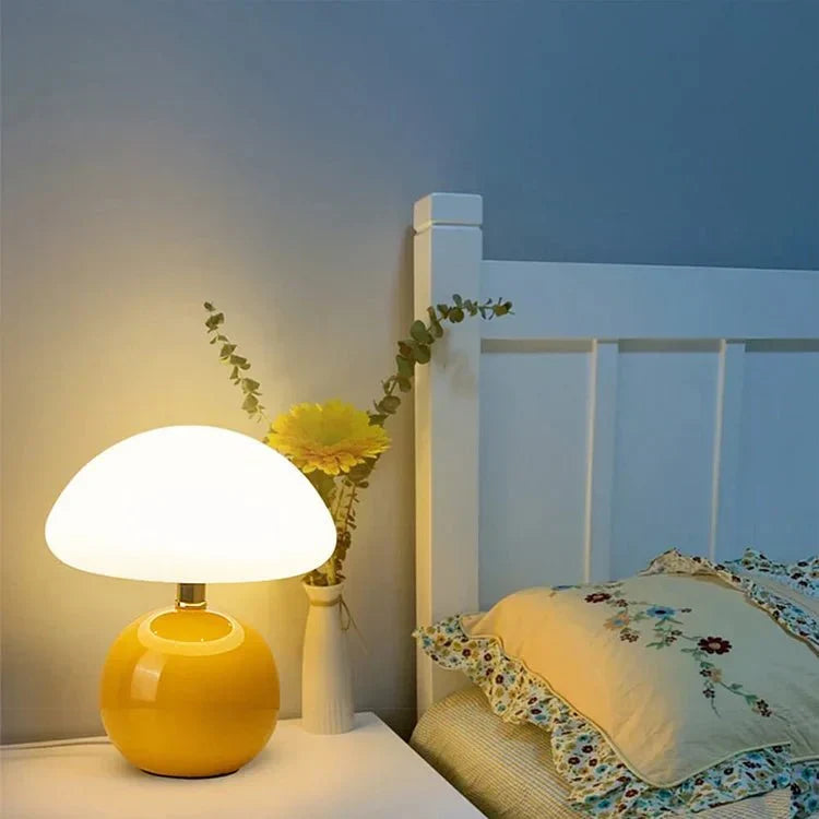 Yellow mushroom lamp lighting a nightstand next to a bed