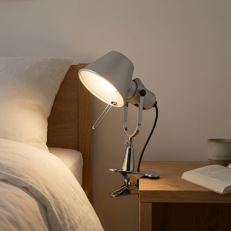 Wall lights for bedroom: clip-on lamp glowing beside a linen bed