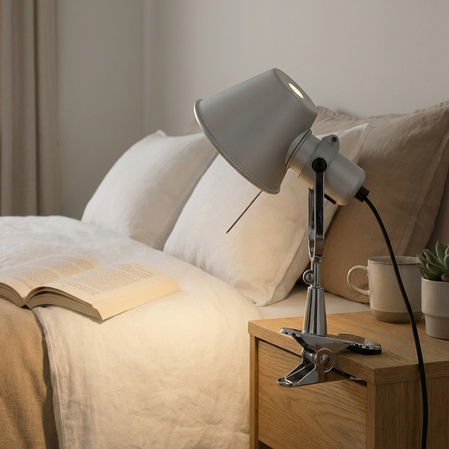 Contemporary clip-on lamp angled over a bed from a nightstand
