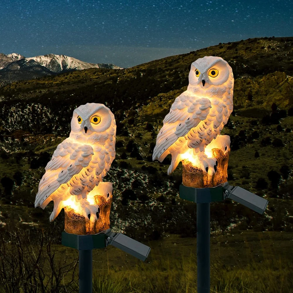 Two glowing owl stake lights against a starry mountain sky