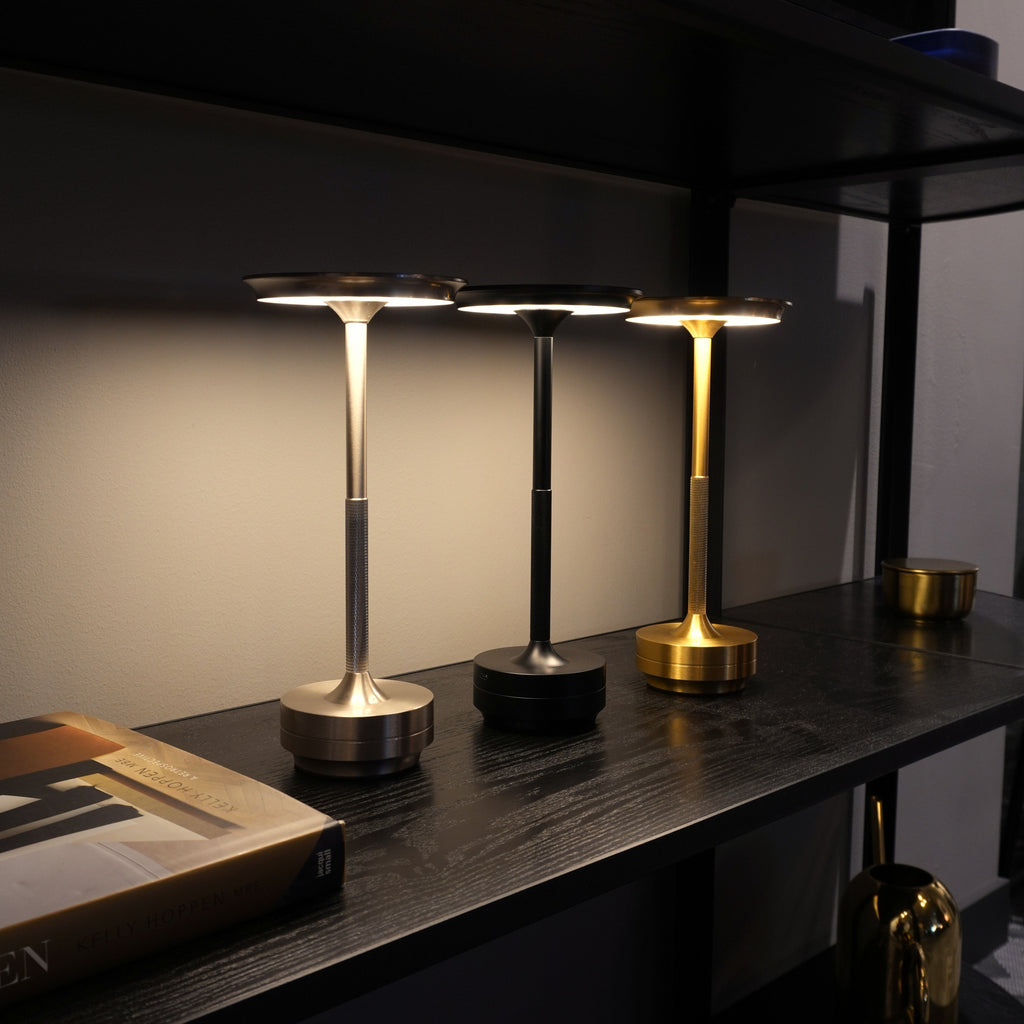 Silver, black and gold modern table lamps on a shelf