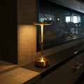 Gold cordless table lamp glowing on a dark stone ledge