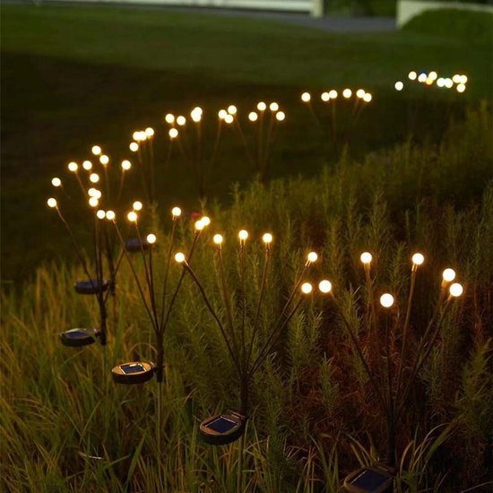 Rows of outdoor landscape lighting glowing in tall grass at dusk